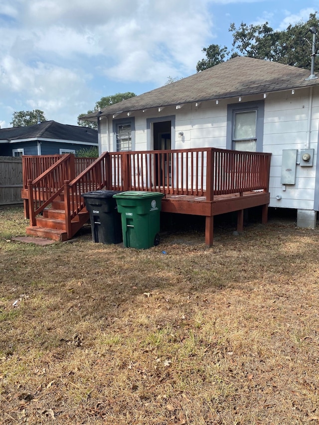 back of property with roof with shingles, a lawn, and a wooden deck