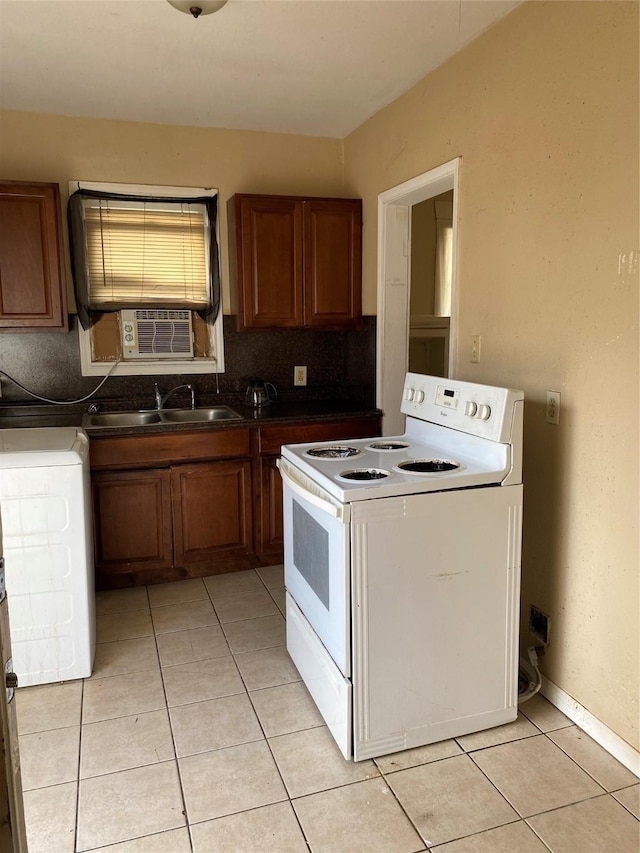 kitchen with white electric range oven, light tile patterned floors, washer / dryer, decorative backsplash, and dark countertops