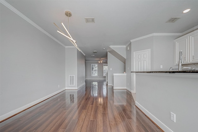 unfurnished living room featuring dark hardwood / wood-style flooring, ceiling fan, and ornamental molding