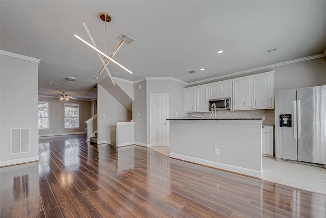 kitchen featuring crown molding, light wood-type flooring, tasteful backsplash, white cabinetry, and stainless steel appliances