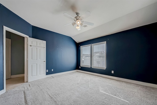 empty room featuring carpet floors, vaulted ceiling, and ceiling fan