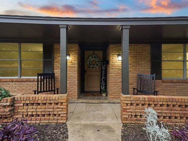 exterior entry at dusk with brick siding and covered porch