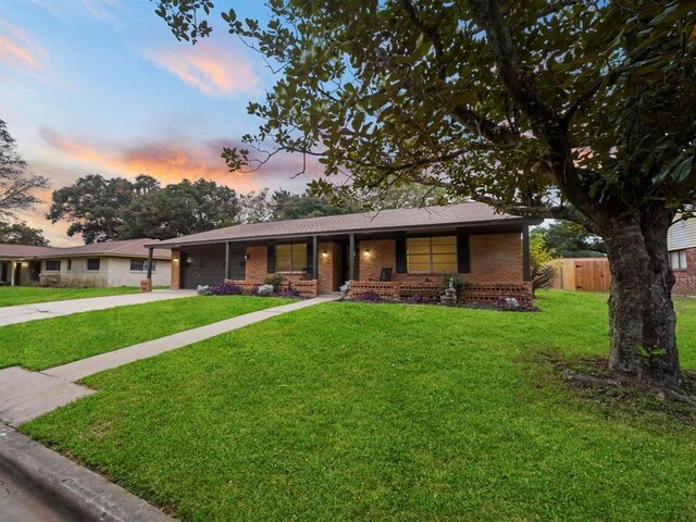 single story home featuring a front lawn, fence, concrete driveway, an attached garage, and brick siding