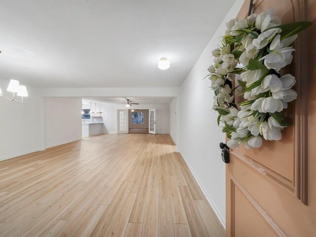 unfurnished living room with light hardwood / wood-style floors and ceiling fan with notable chandelier