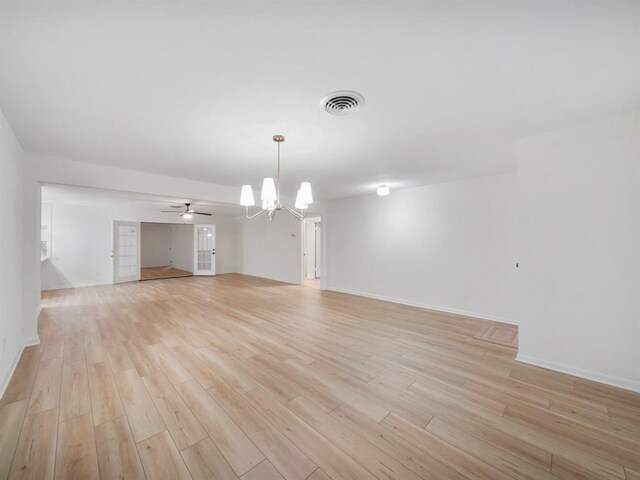 interior space with ceiling fan with notable chandelier, visible vents, light wood finished floors, and baseboards