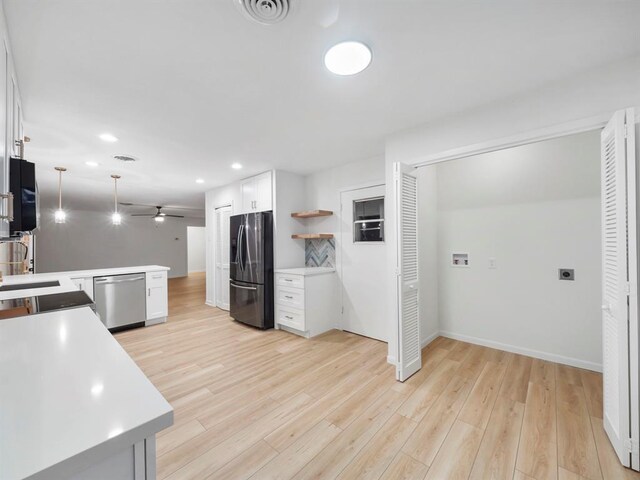 kitchen with white cabinetry, kitchen peninsula, appliances with stainless steel finishes, and light hardwood / wood-style flooring