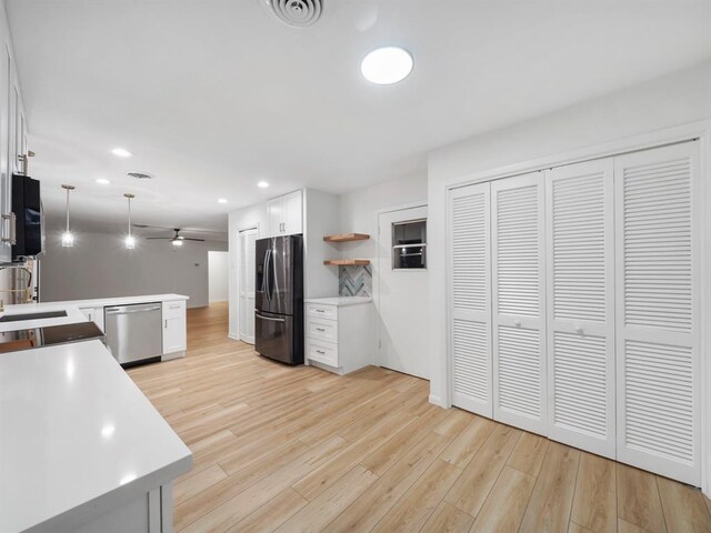 kitchen with kitchen peninsula, stainless steel appliances, ceiling fan, pendant lighting, and white cabinets