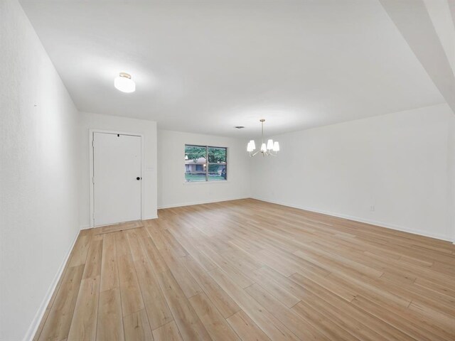 spare room featuring a chandelier and light wood-type flooring