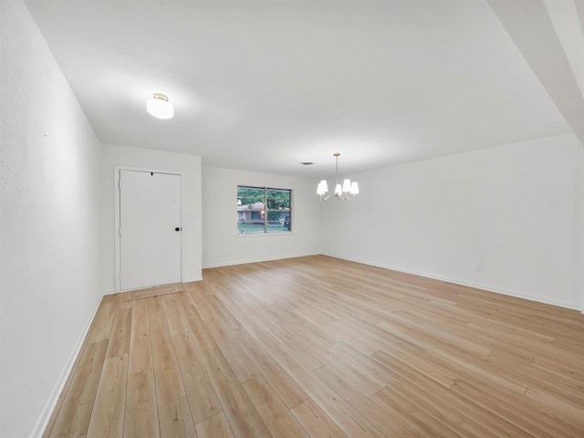 unfurnished room with baseboards, a chandelier, and light wood finished floors