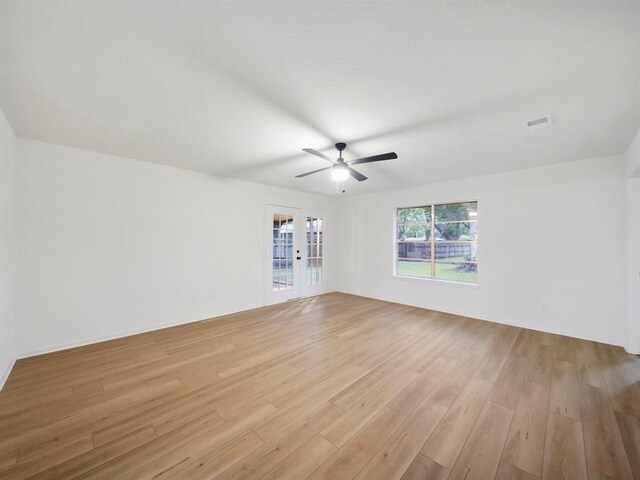 empty room with visible vents, light wood-style flooring, french doors, and ceiling fan