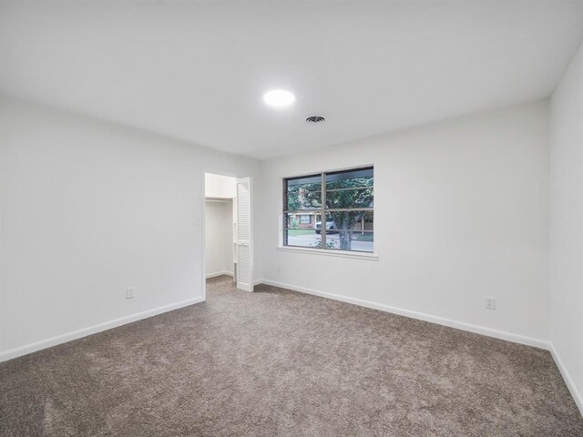 carpeted empty room featuring baseboards and visible vents