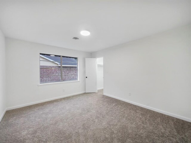 carpeted empty room with visible vents and baseboards