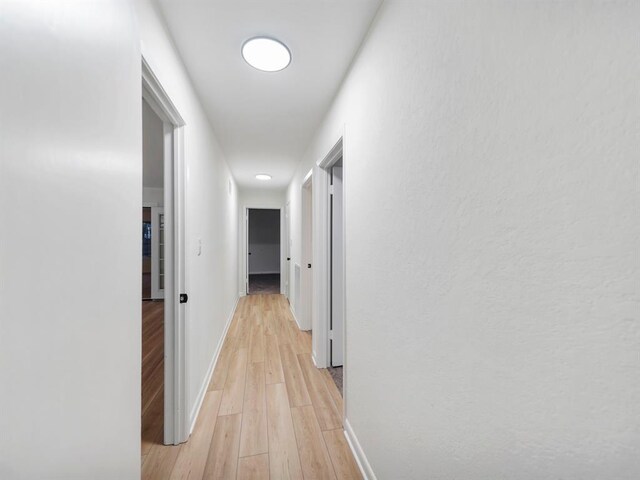 corridor with light wood finished floors and baseboards