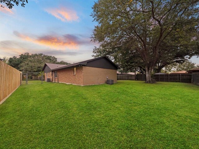 yard at dusk featuring a fenced backyard