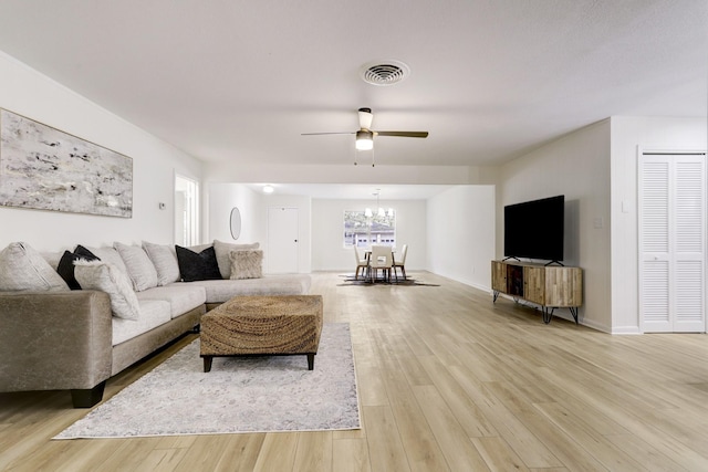 living area with visible vents, ceiling fan with notable chandelier, light wood-style flooring, and baseboards