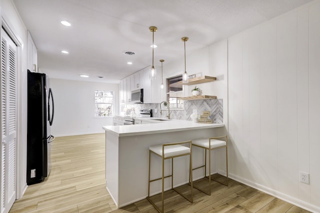 kitchen featuring a sink, stainless steel appliances, light wood-type flooring, and visible vents