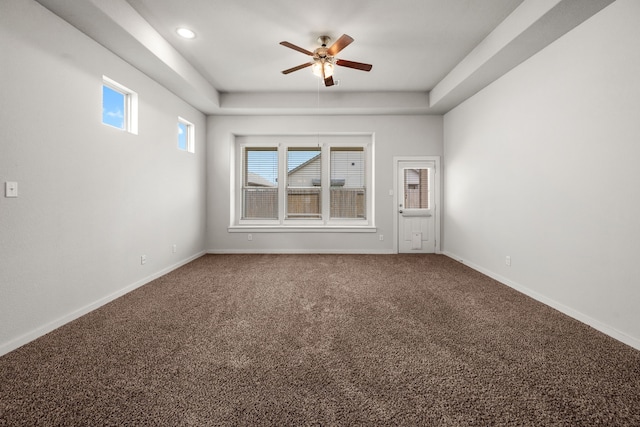 carpeted empty room with a tray ceiling and ceiling fan