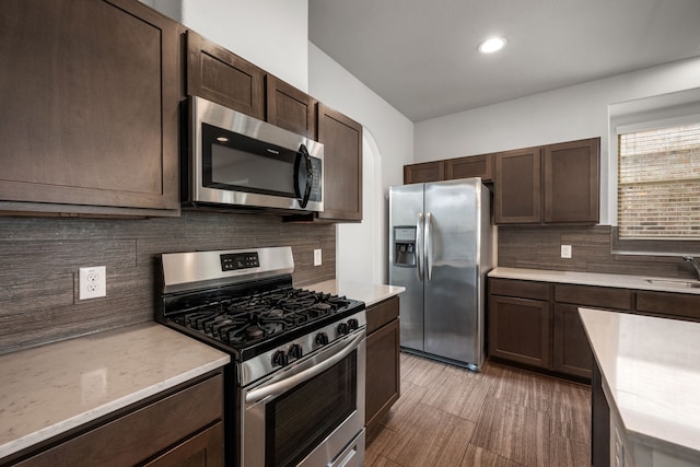 kitchen featuring appliances with stainless steel finishes, decorative backsplash, sink, and dark brown cabinets