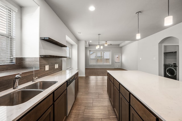 kitchen with sink, washer / clothes dryer, decorative light fixtures, and stainless steel dishwasher