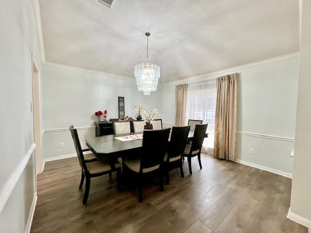 dining space featuring hardwood / wood-style floors, crown molding, and an inviting chandelier