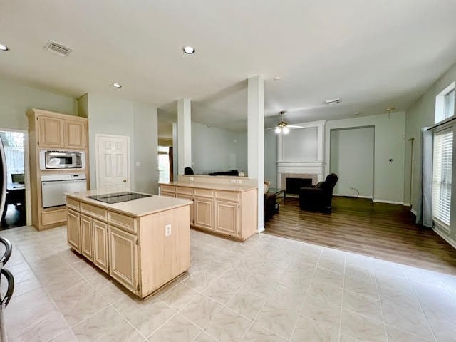 kitchen featuring light brown cabinets, white oven, ceiling fan, a kitchen island, and stainless steel microwave