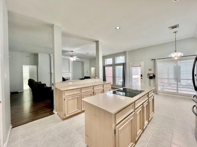 kitchen featuring black electric stovetop, light brown cabinets, light hardwood / wood-style flooring, hanging light fixtures, and a center island