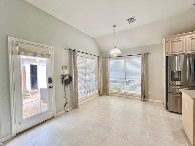 interior space featuring hanging light fixtures, stainless steel fridge, vaulted ceiling, light tile patterned floors, and light brown cabinetry