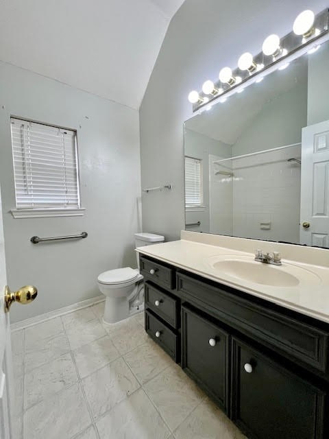 bathroom with toilet, vanity, a shower, and vaulted ceiling