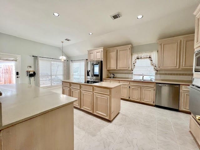 kitchen with a kitchen island, stainless steel appliances, lofted ceiling, decorative light fixtures, and decorative backsplash