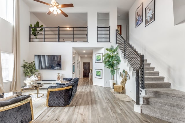 living room with a towering ceiling, hardwood / wood-style floors, and ceiling fan