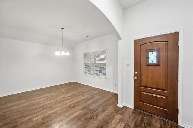 foyer with lofted ceiling, dark wood-type flooring, and a notable chandelier