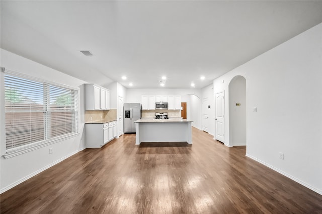 kitchen featuring tasteful backsplash, appliances with stainless steel finishes, an island with sink, white cabinetry, and dark wood-type flooring