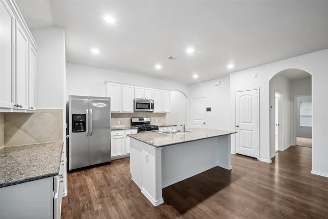 kitchen with dark hardwood / wood-style floors, a center island with sink, sink, light stone countertops, and appliances with stainless steel finishes