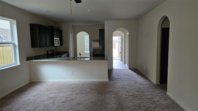 kitchen featuring kitchen peninsula, stainless steel appliances, sink, and dark colored carpet