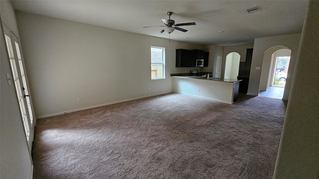 kitchen featuring a kitchen bar, dark colored carpet, kitchen peninsula, and ceiling fan