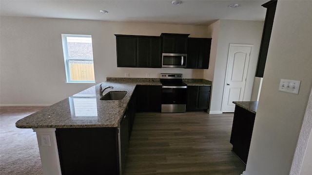 kitchen featuring light stone countertops, sink, kitchen peninsula, stainless steel appliances, and dark hardwood / wood-style floors