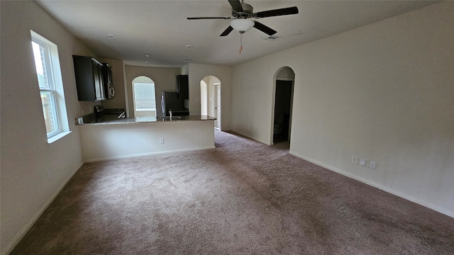 unfurnished living room with ceiling fan and dark colored carpet