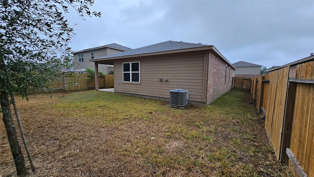 back of house with central AC and a lawn