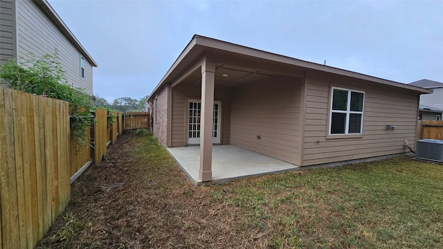 rear view of house with a patio area, central AC, and a lawn