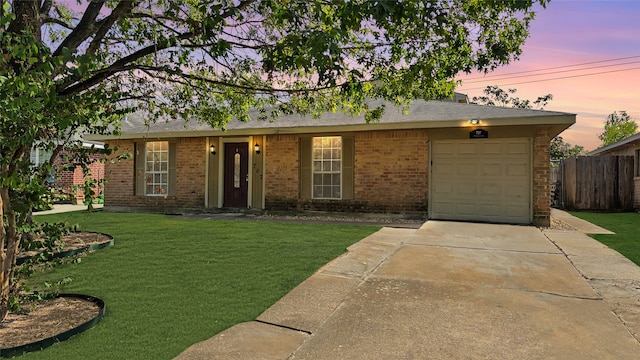 ranch-style home featuring a lawn and a garage