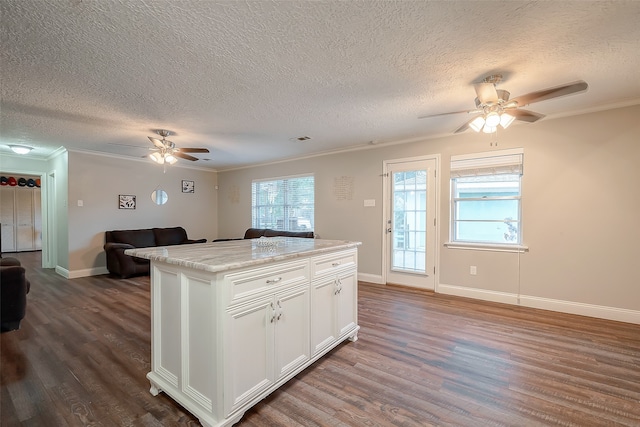 kitchen with a kitchen island, a textured ceiling, white cabinetry, dark wood-type flooring, and crown molding