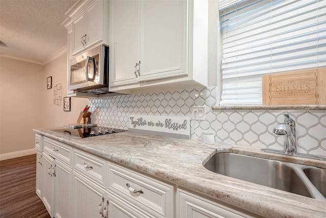 kitchen with sink, white cabinetry, crown molding, and black electric cooktop