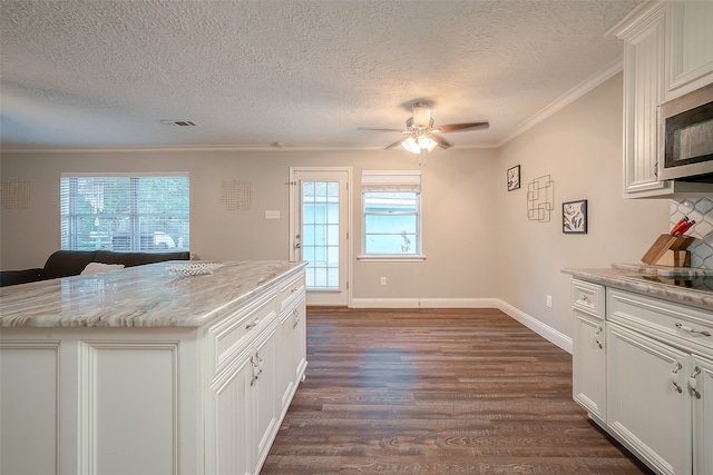 kitchen with a wealth of natural light, crown molding, a center island, and dark hardwood / wood-style flooring