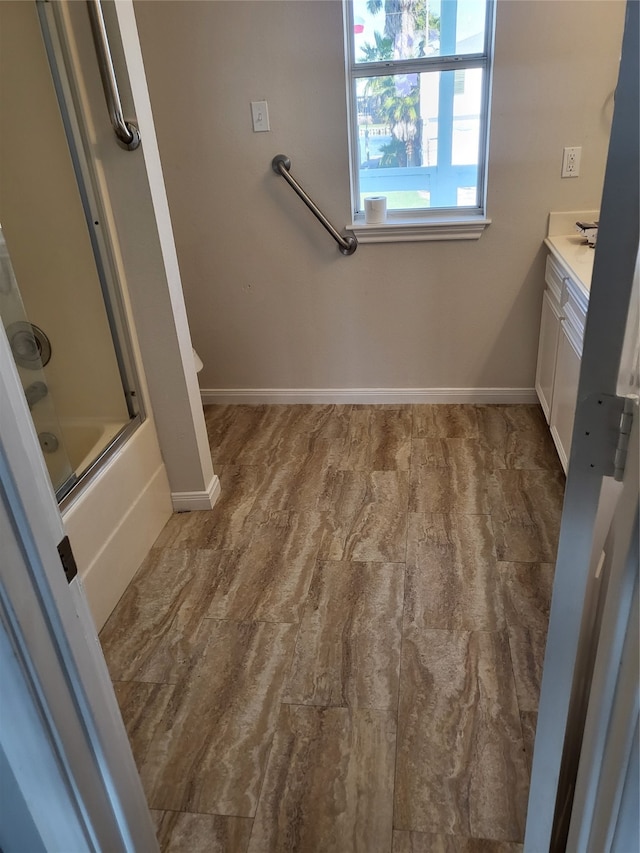 full bathroom featuring combined bath / shower with glass door, wood-type flooring, vanity, and toilet