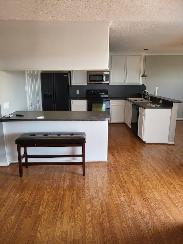 kitchen with black appliances, pendant lighting, light wood-type flooring, and kitchen peninsula