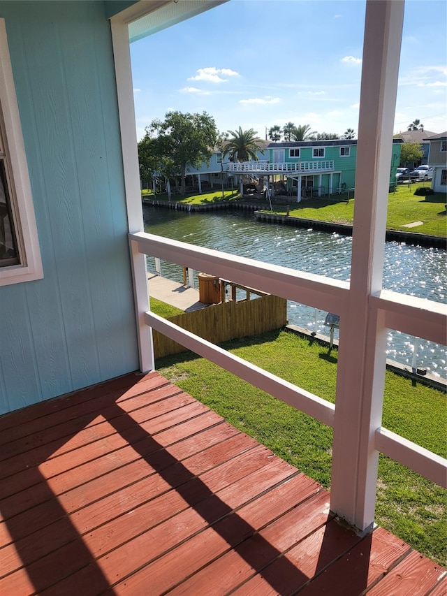 wooden terrace with a water view and a lawn