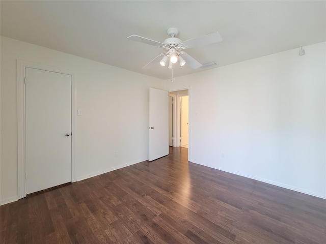 unfurnished room with dark wood-type flooring, ceiling fan, and baseboards