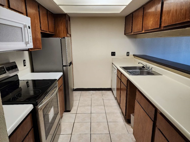 kitchen featuring sink, light tile patterned floors, and white appliances