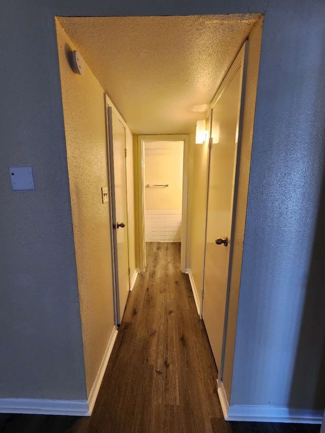 hall with dark wood-type flooring and a textured ceiling