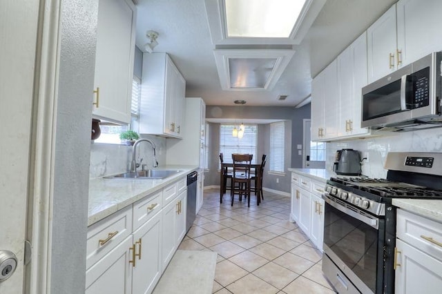 kitchen featuring light tile patterned flooring, appliances with stainless steel finishes, decorative backsplash, sink, and white cabinets